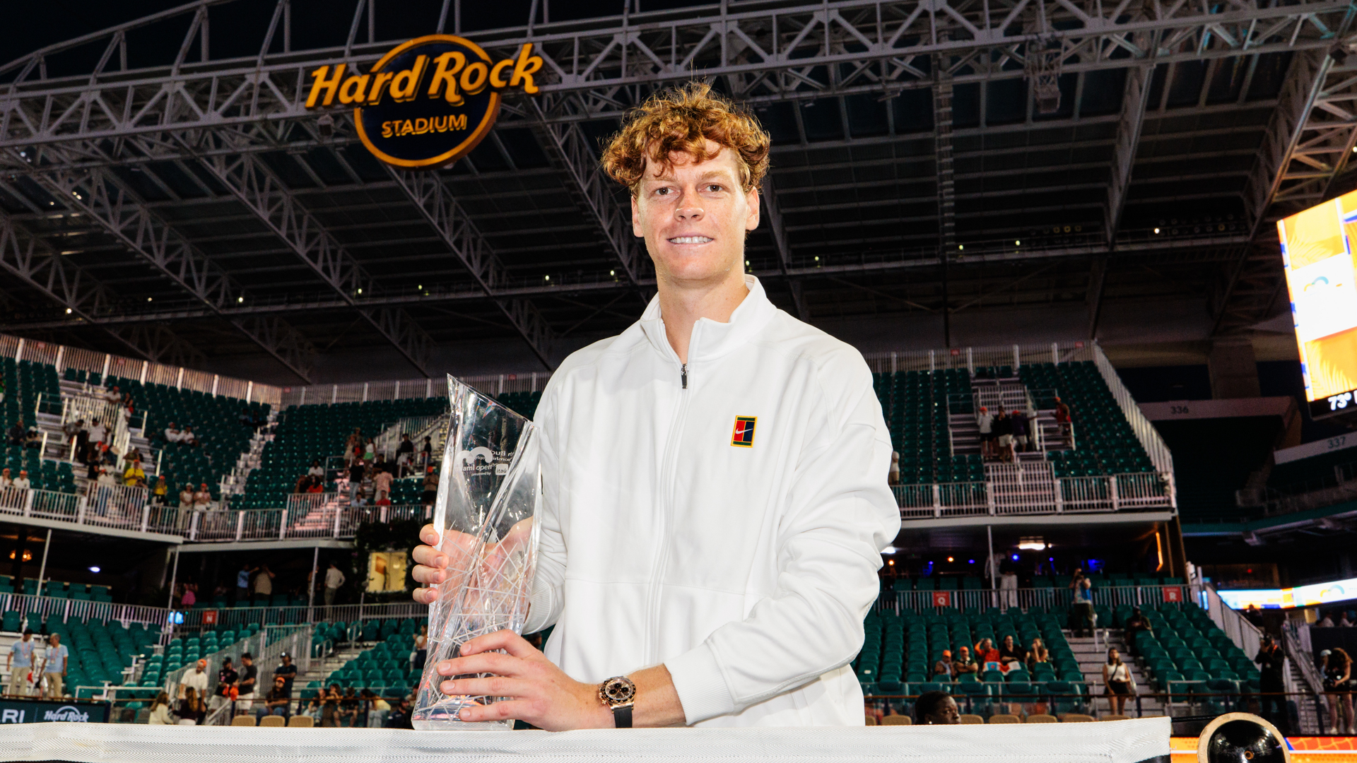 The men's champion holding the trophy beneath the Hard Rock Stadium sign
