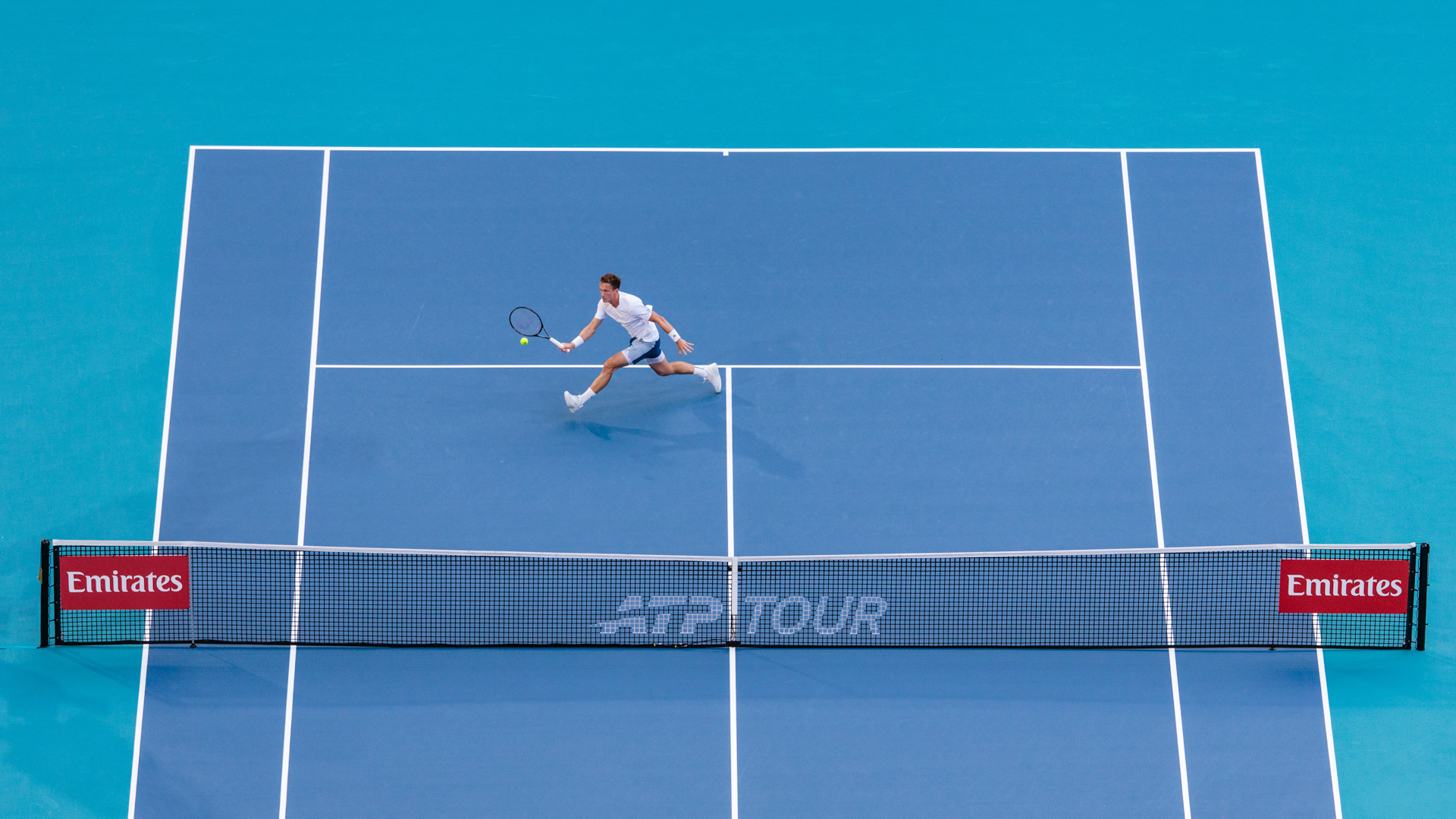Aerial view of a player stretching for a shot on the blue stadium court
